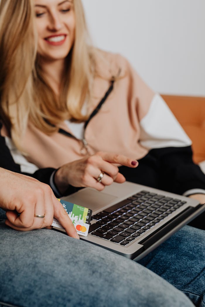 A smiling couple shopping online using a laptop and credit card, highlighting modern lifestyle and technology.